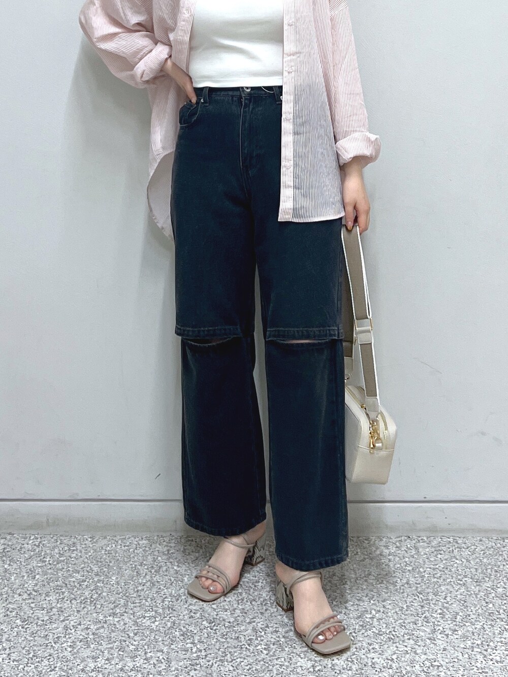 ブラック系のデニムパンツ、グレー系のサンダル、ホワイト系のハンドバッグを着用したレディースの夏コーディネートの5枚目の写真