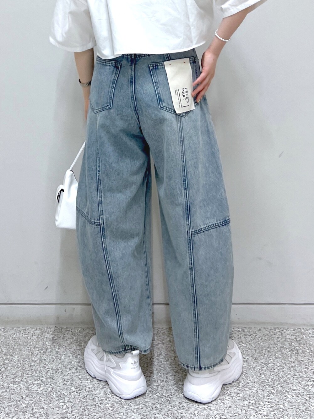 ホワイト系のハンドバッグ、ブルー系のデニムパンツ、ホワイト系のシャツ/ブラウスを着用したレディースの夏コーディネートの6枚目の写真