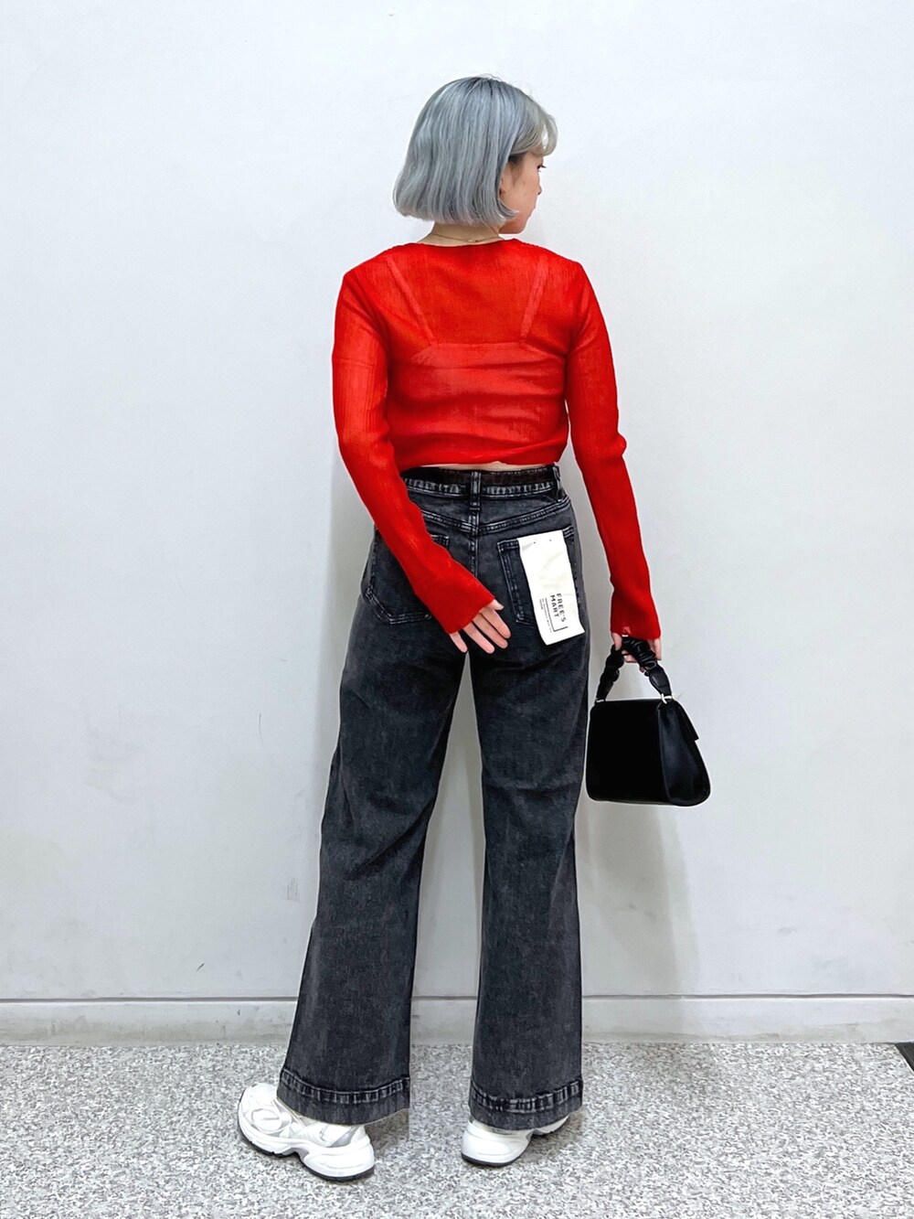 レッド系のカーディガン/ボレロ、ブラック系のデニムパンツ、ブラック系のショルダーバッグを着用したレディースの秋コーディネートの2枚目の写真