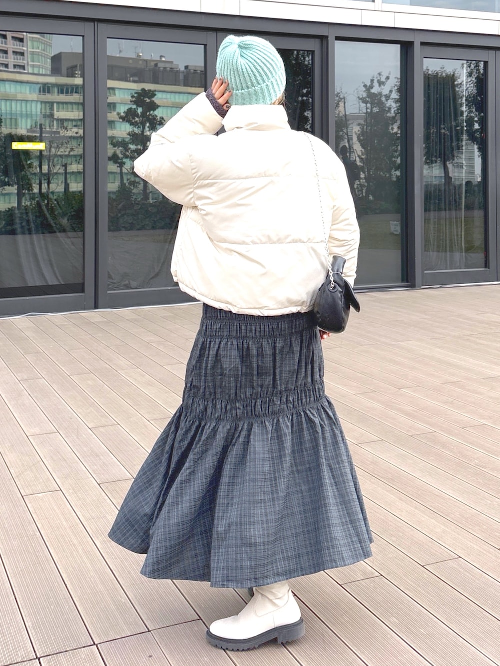 ブラック系のスカート、グリーン系のブルゾン、ブラック系のショルダーバッグを着用したレディースの冬コーディネートの2枚目の写真