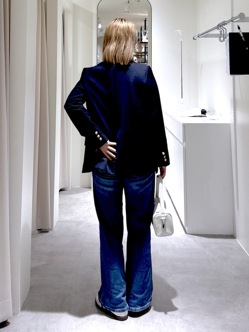 ホワイト系のハンドバッグ、ブルー系のテーラードジャケット、グレー系のニット/セーターを着用したレディースの春コーディネートの3枚目の写真