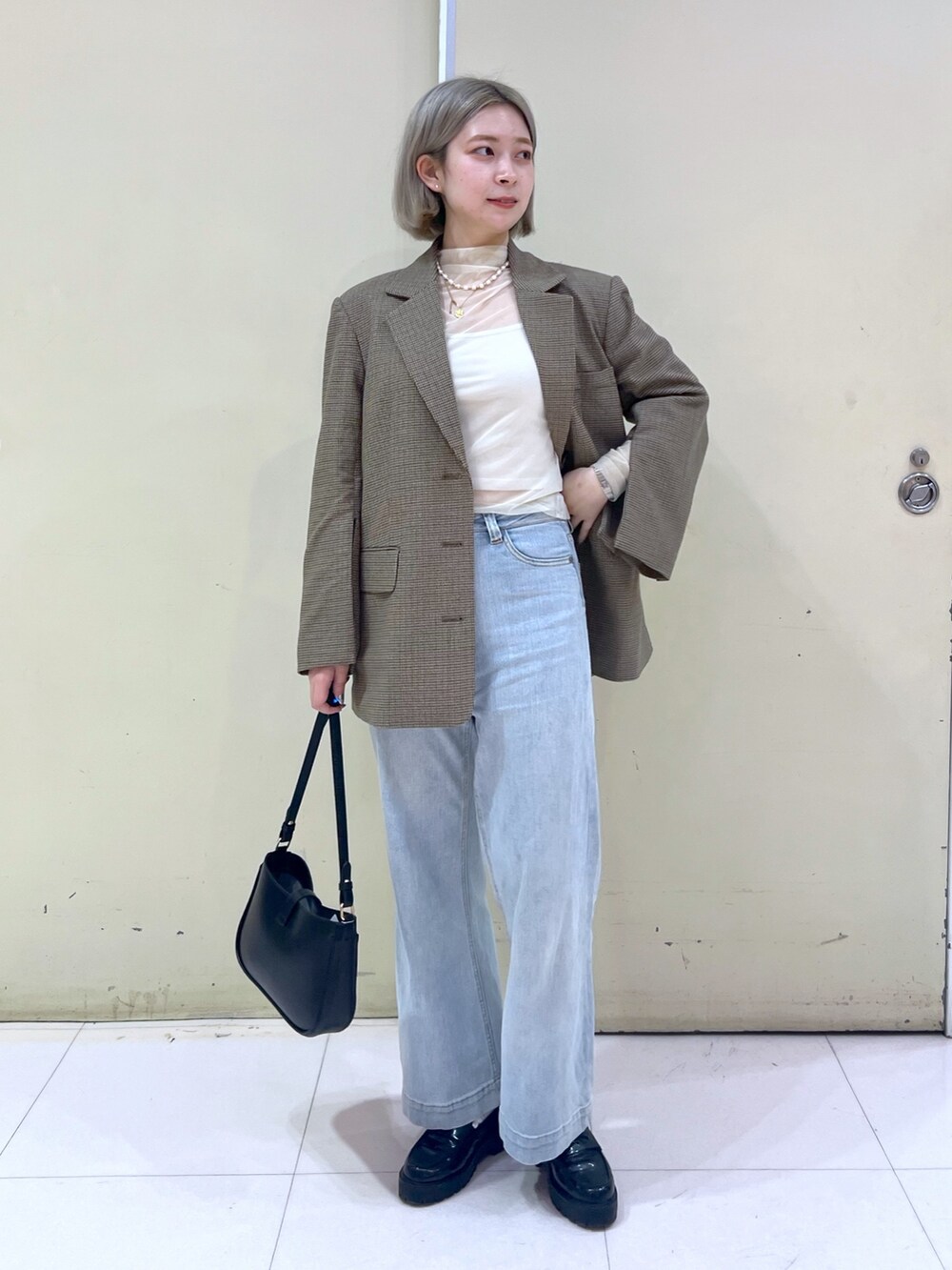 ブラウン系のテーラードジャケット、ホワイト系のTシャツ/カットソー、ベージュ系のショルダーバッグを着用したレディースの春コーディネートの2枚目の写真