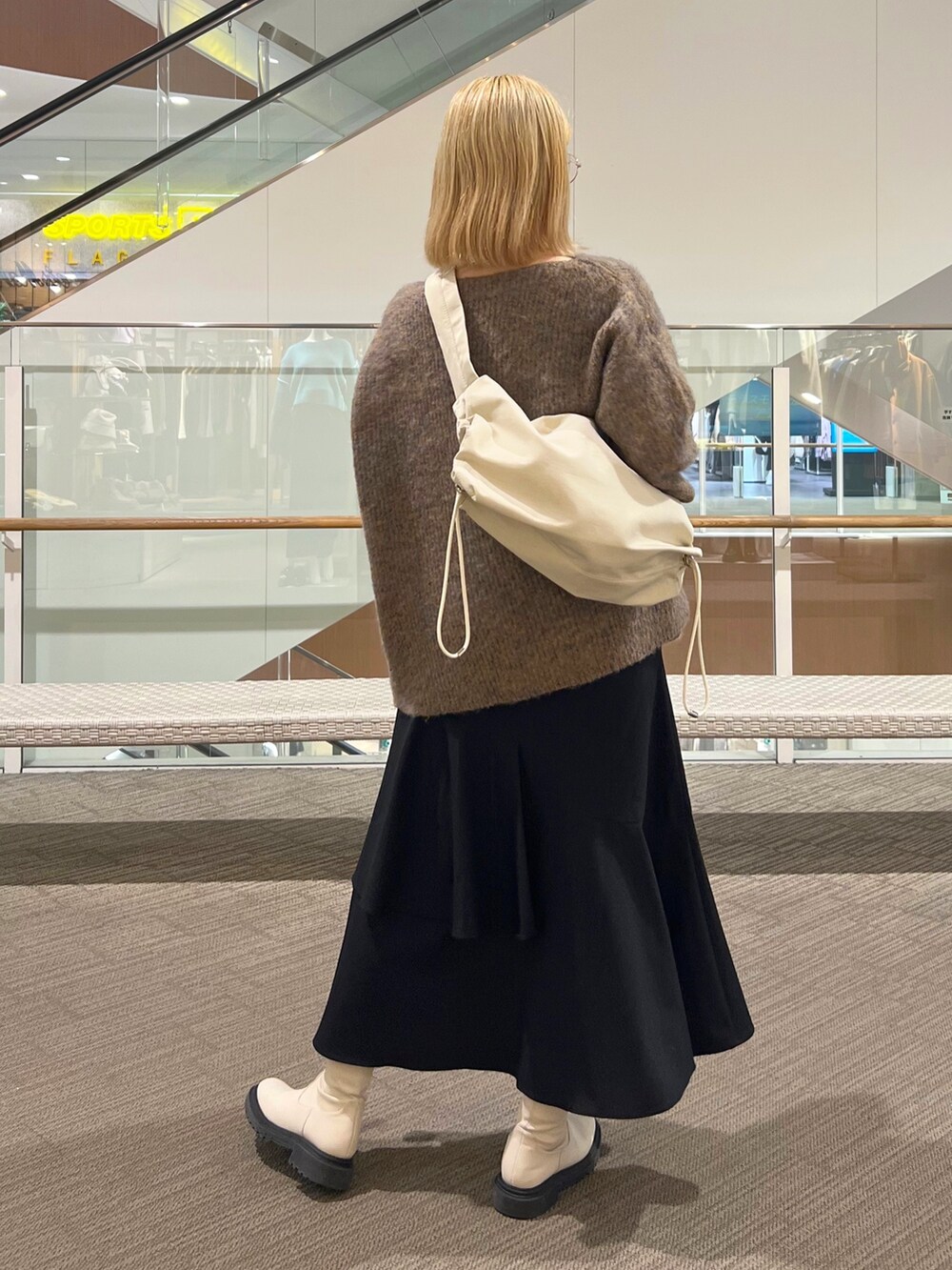 ブラック系のスカート、ベージュ系のニット/セーター、ホワイト系のショルダーバッグを着用したレディースの冬コーディネートの3枚目の写真