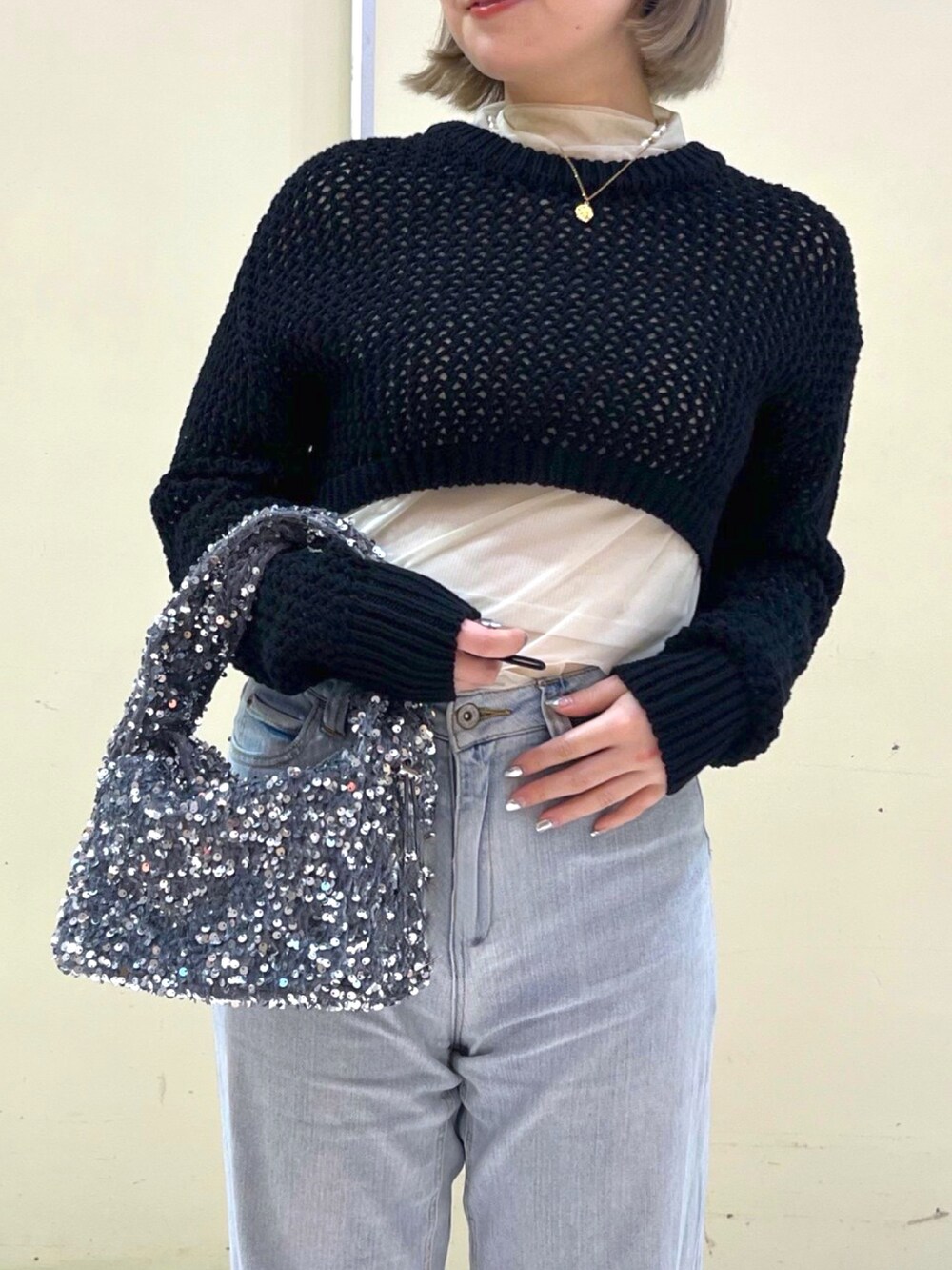 ブラック系のニット/セーター、ブルー系のデニムパンツ、シルバー系のハンドバッグを着用したレディースの春コーディネートの4枚目の写真