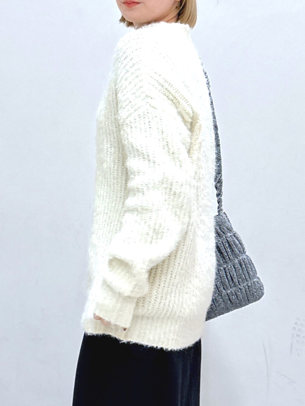 ブラック系のスカート、ホワイト系のニット/セーター、シルバー系のショルダーバッグを着用したレディースの冬コーディネートの5枚目の写真