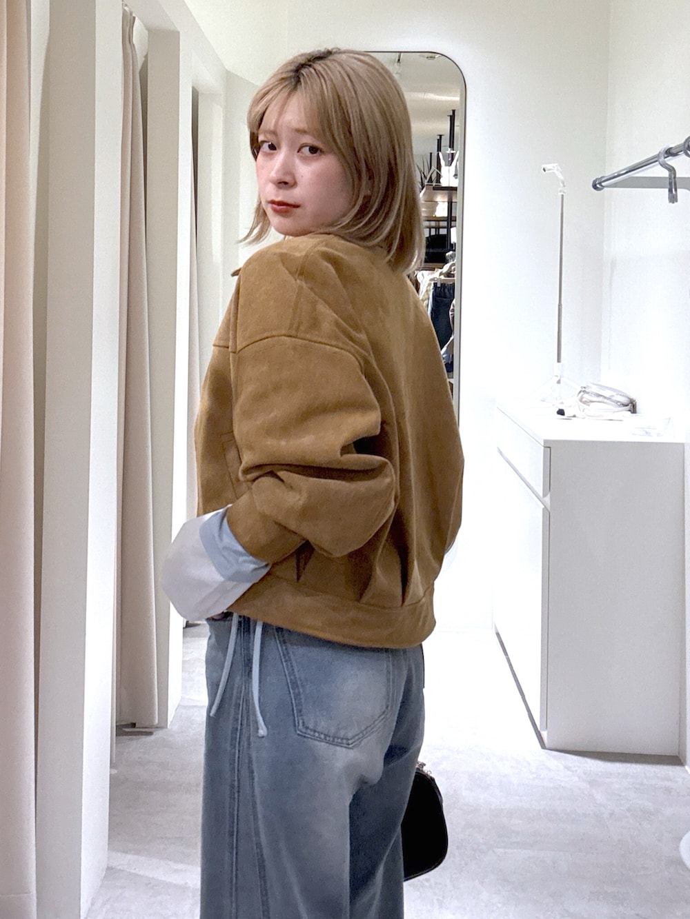 ブルー系のデニムパンツ、ブラック系のハンドバッグ、ブルー系のTシャツ/カットソーを着用したレディースの春コーディネートの4枚目の写真