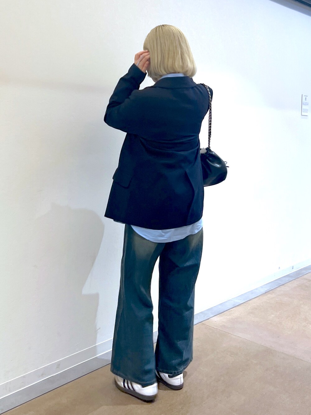 ブラック系のショルダーバッグ、ブルー系のデニムパンツ、ブルー系のテーラードジャケットを着用したレディースの秋コーディネートの2枚目の写真