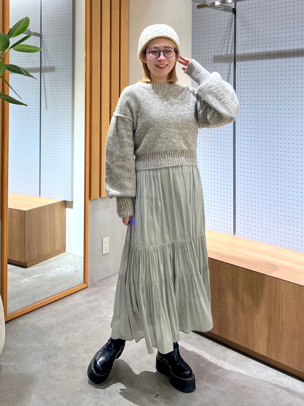 グレー系のニット/セーター、グリーン系のスカート、ベージュ系のショルダーバッグを着用したレディースの冬コーディネートの5枚目の写真