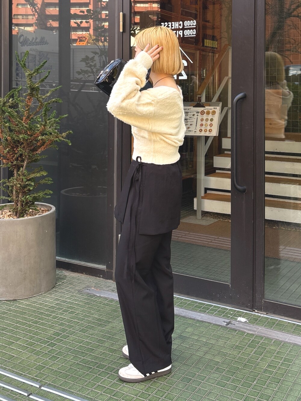 ブラック系のその他パンツ、ホワイト系のニット/セーター、ブラック系のショルダーバッグを着用したレディースの春コーディネートの2枚目の写真
