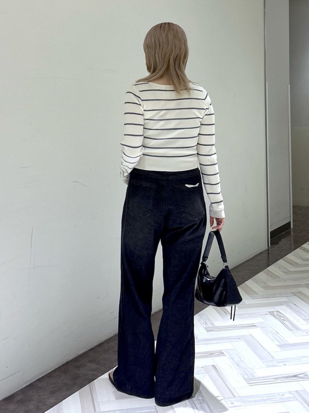 ブラック系のデニムパンツ、ホワイト系のニット/セーター、ブラック系のショルダーバッグを着用したレディースの秋コーディネートの3枚目の写真