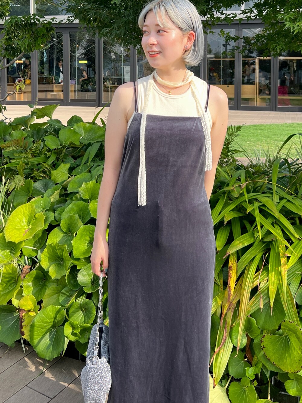 シルバー系のハンドバッグ、ブルー系のデニムパンツ、ホワイト系のタンクトップを着用したレディースの秋コーディネートの4枚目の写真