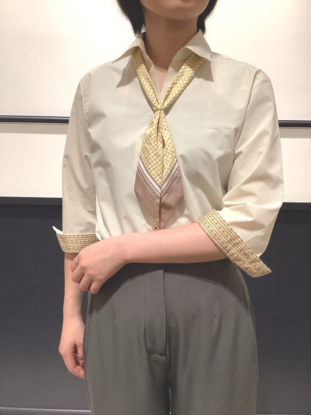 イエロー系のビジネスシャツ、イエロー系のストール/ショールを着用したレディースの夏コーディネートの2枚目の写真