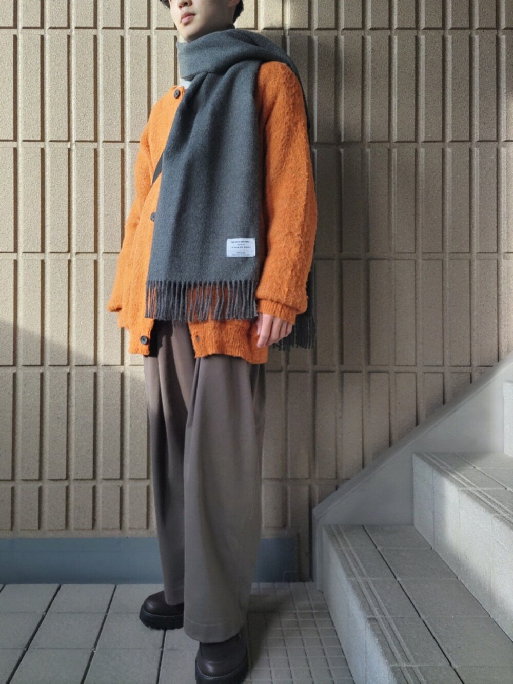 オレンジ系のカーディガン/ボレロ、グレー系のシャツ/ブラウス、グレー系のその他パンツを着用したメンズの冬コーディネートの2枚目の写真