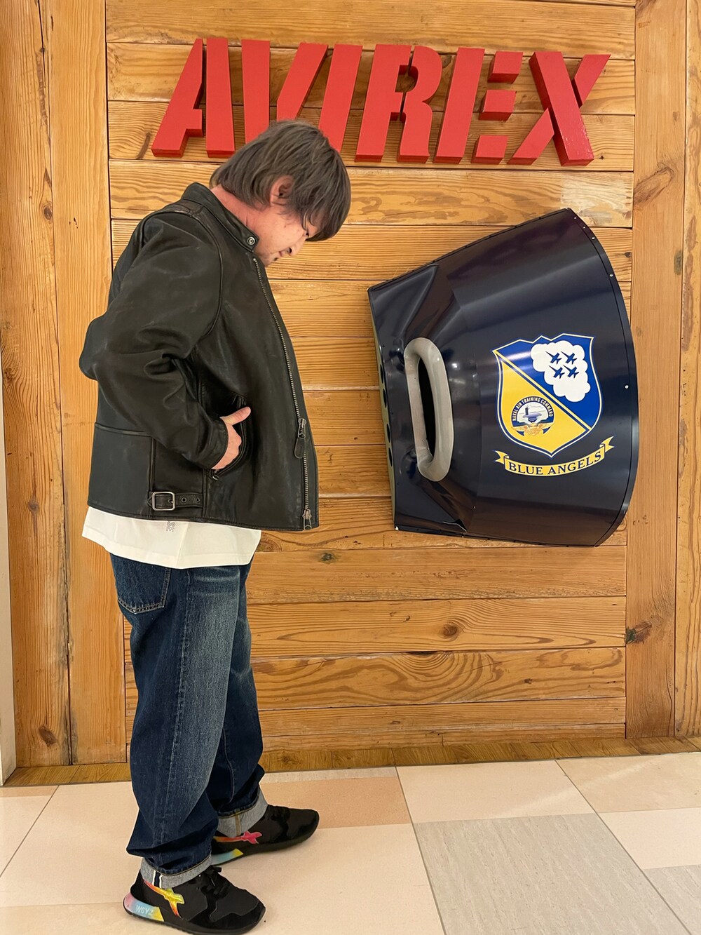 ホワイト系のトップス、ブラック系のライダースジャケット、ブルー系のデニムパンツを着用したメンズの春コーディネートの2枚目の写真