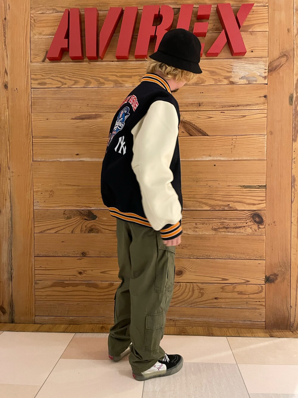 ブルー系のスタジャン、ホワイト系のTシャツ/カットソー、グリーン系のカーゴパンツを着用したメンズの秋コーディネートの4枚目の写真