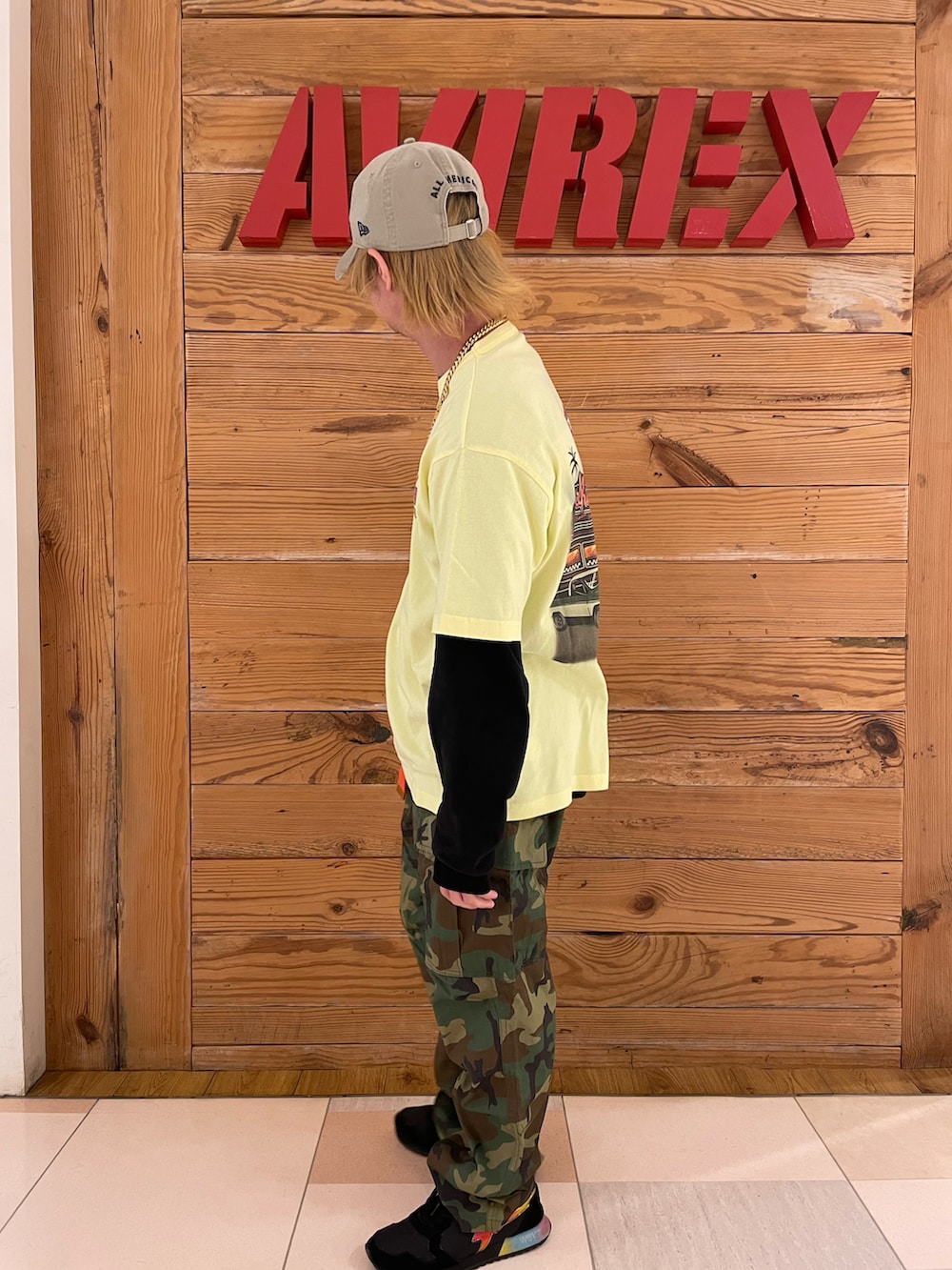 イエロー系のTシャツ/カットソー、グリーン系のカーゴパンツ、その他のキャップを着用したメンズの春コーディネートの2枚目の写真