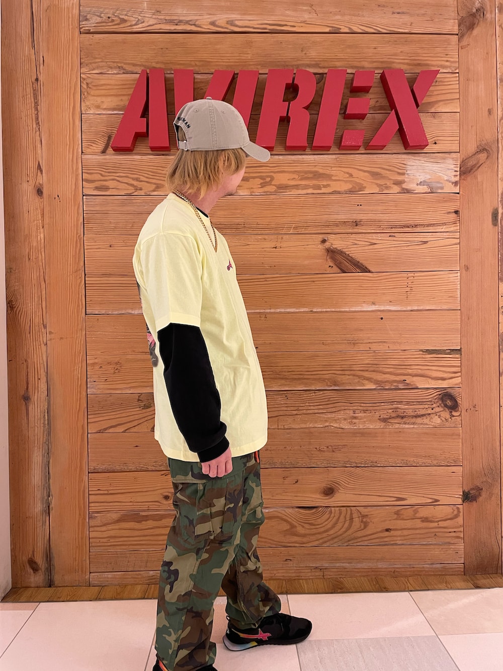 イエロー系のTシャツ/カットソー、グリーン系のカーゴパンツ、その他のキャップを着用したメンズの春コーディネートの4枚目の写真