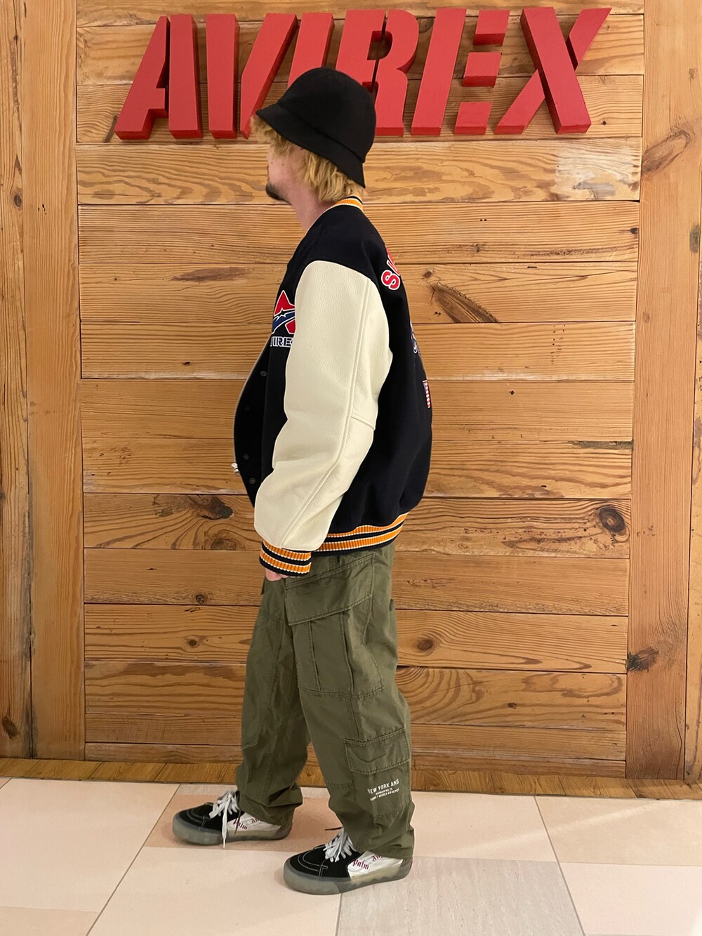 ブルー系のスタジャン、ホワイト系のTシャツ/カットソー、グリーン系のカーゴパンツを着用したメンズの秋コーディネートの2枚目の写真