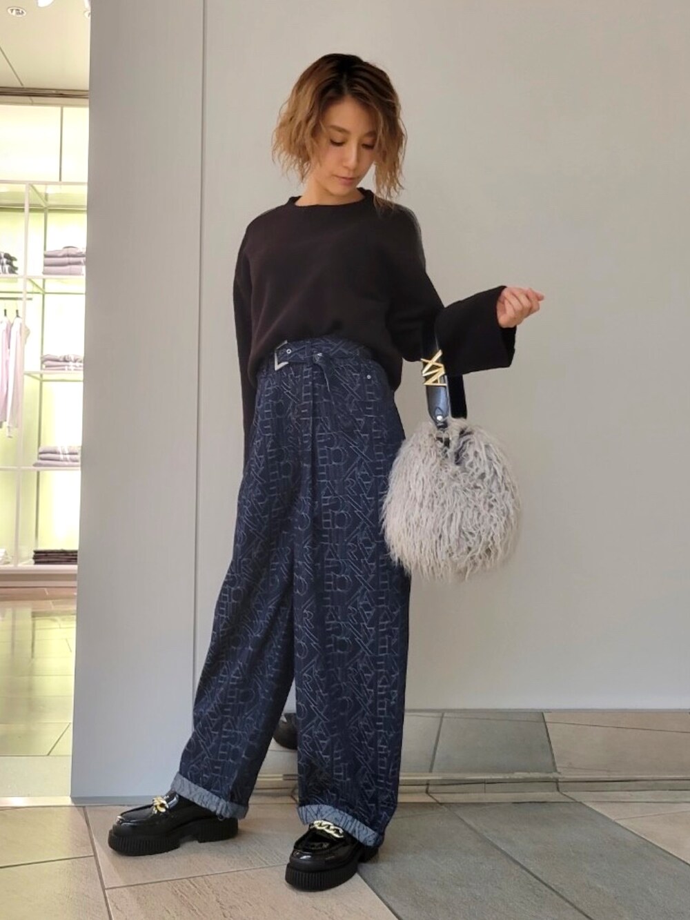 ブラック系のニット/セーター、ブルー系のデニムパンツ、ベージュ系のハンドバッグを着用したレディースの秋コーディネートの2枚目の写真