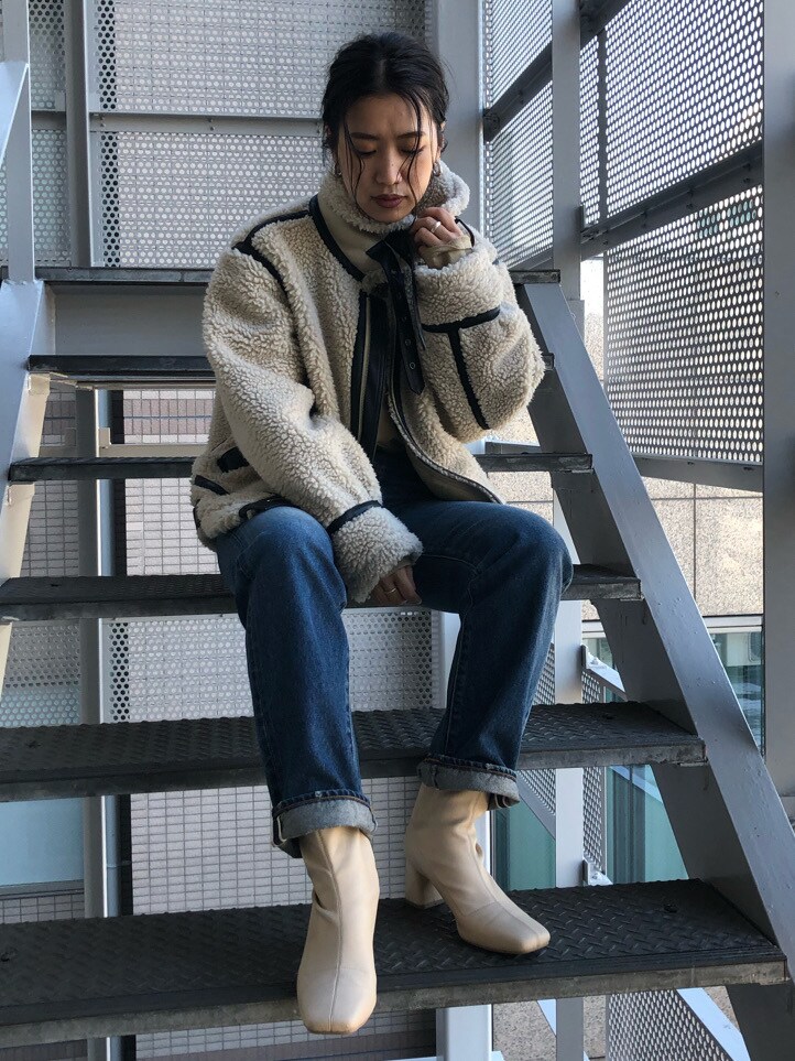 ブルー系のデニムパンツ、ベージュ系のムートンコートを着用したレディースの冬コーディネートの2枚目の写真