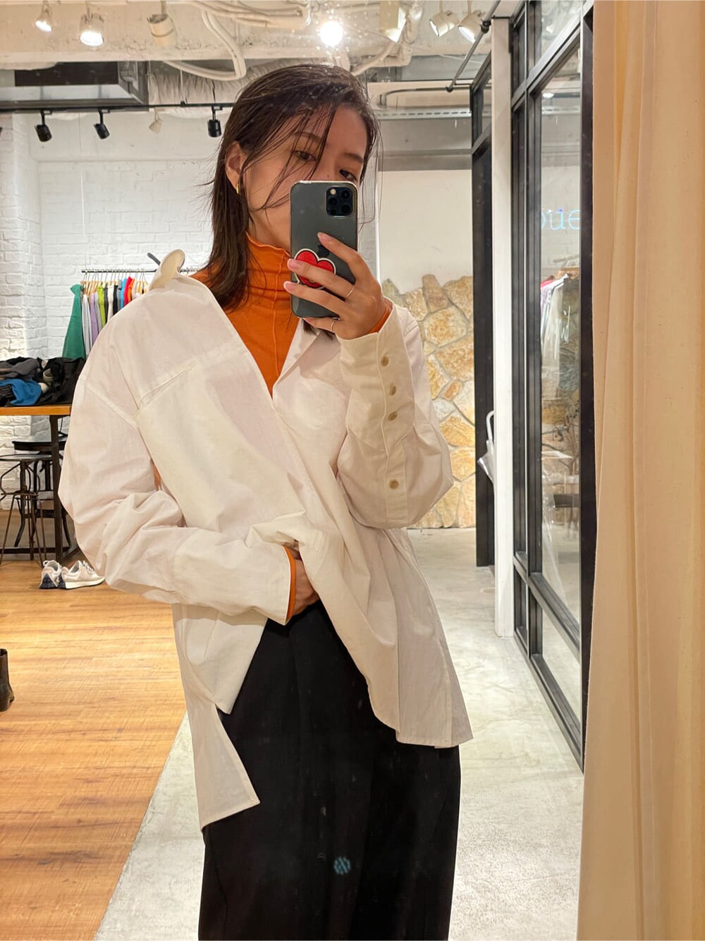 グレー系のスラックス、ホワイト系のシャツ/ブラウス、オレンジ系のTシャツ/カットソーを着用したレディースの秋コーディネートの5枚目の写真