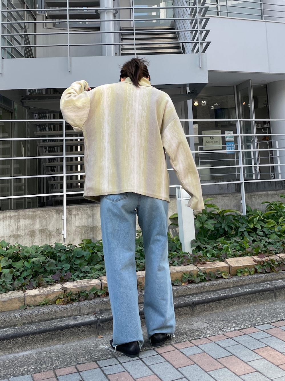 ブルー系のデニムパンツ、グリーン系のカーディガン/ボレロ、ブラック系のパンプスを着用したレディースの秋コーディネートの5枚目の写真