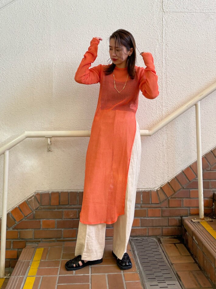 オレンジ系のワンピース、ブラック系のサンダル、ホワイト系のその他パンツを着用したレディースの春コーディネートの2枚目の写真