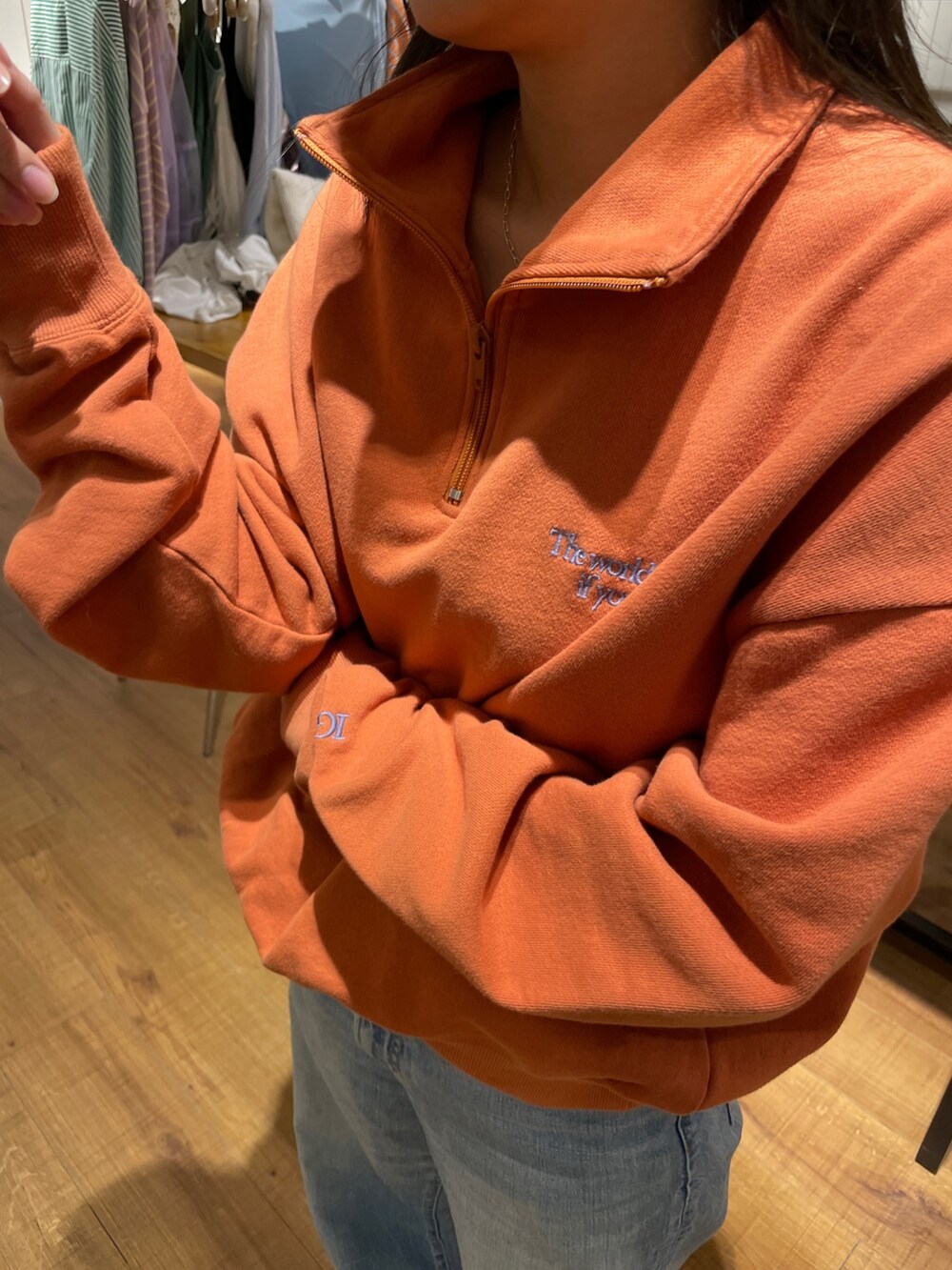 オレンジ系のスウェット、ブルー系のデニムパンツを着用したレディースの冬コーディネートの3枚目の写真