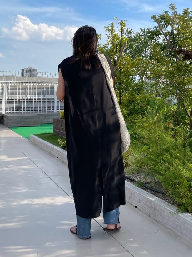 ブラック系のワンピース、ブルー系のデニムパンツを着用したレディースの夏コーディネートの5枚目の写真