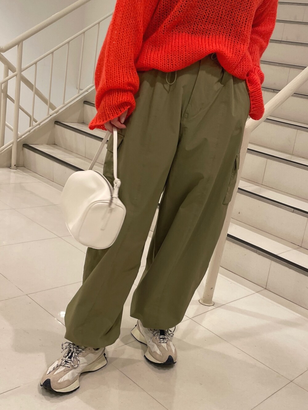 グリーン系のカーゴパンツ、ホワイト系のハンドバッグ、オレンジ系のニット/セーターを着用したレディースの冬コーディネートの7枚目の写真