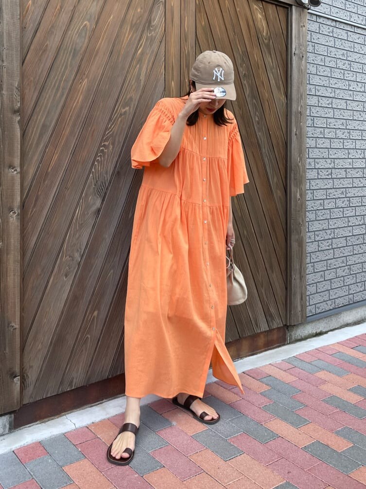 オレンジ系のワンピース、ベージュ系のハンドバッグ、ブラウン系のサンダルを着用したレディースの春コーディネートの6枚目の写真