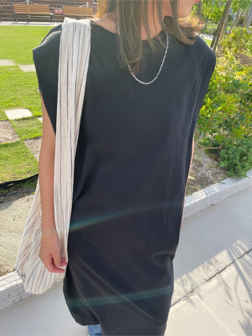 ブラック系のワンピース、ブルー系のデニムパンツを着用したレディースの夏コーディネートの7枚目の写真