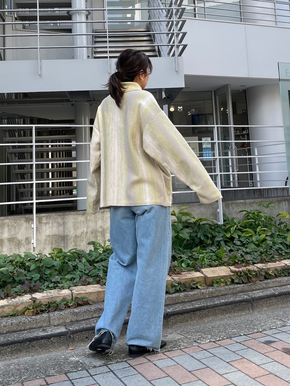 ブルー系のデニムパンツ、グリーン系のカーディガン/ボレロ、ブラック系のパンプスを着用したレディースの秋コーディネートの4枚目の写真