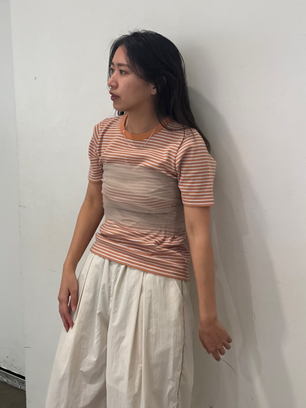 ホワイト系のその他パンツ、オレンジ系のTシャツ/カットソー、ベージュ系のキャミソールを着用したレディースの春コーディネートの3枚目の写真