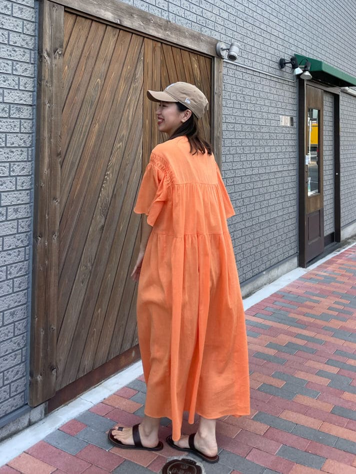 オレンジ系のワンピース、ベージュ系のハンドバッグ、ブラウン系のサンダルを着用したレディースの春コーディネートの7枚目の写真