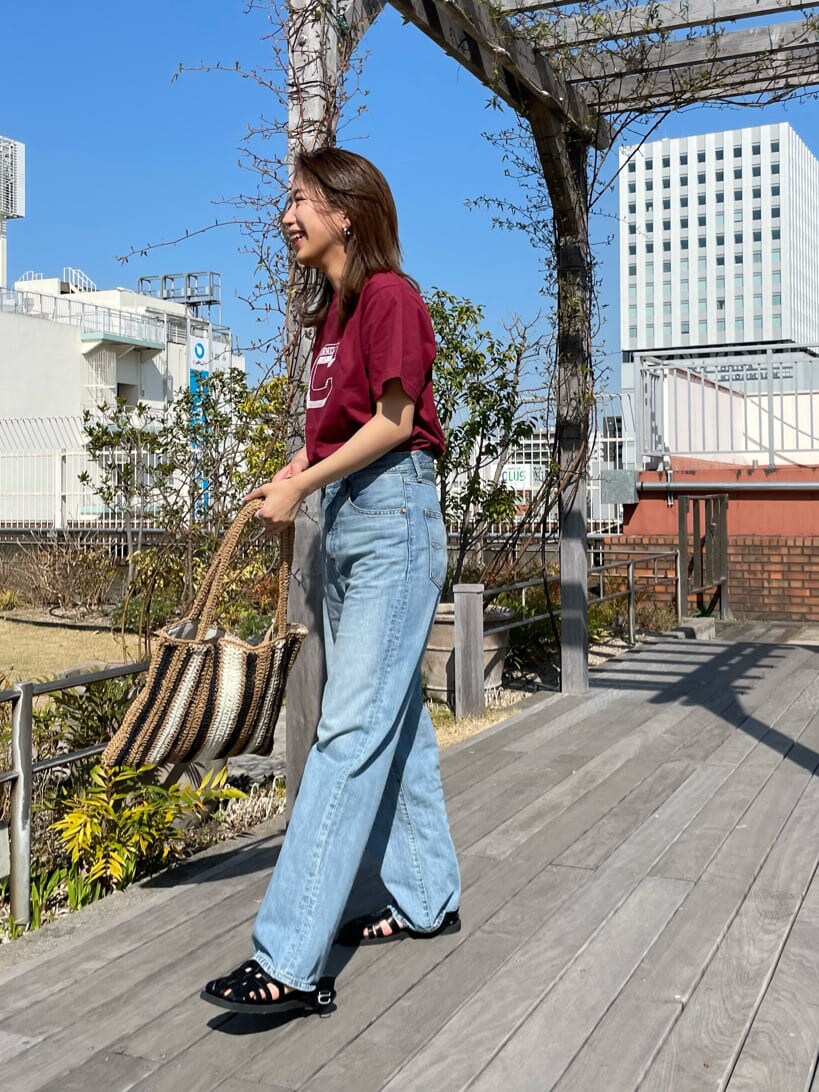 ベージュ系のトートバッグ、ブラック系のサンダル、ブルー系のデニムパンツを着用したレディースの春コーディネートの2枚目の写真