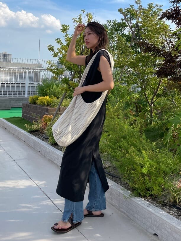 ブラック系のワンピース、ブルー系のデニムパンツを着用したレディースの夏コーディネートの2枚目の写真