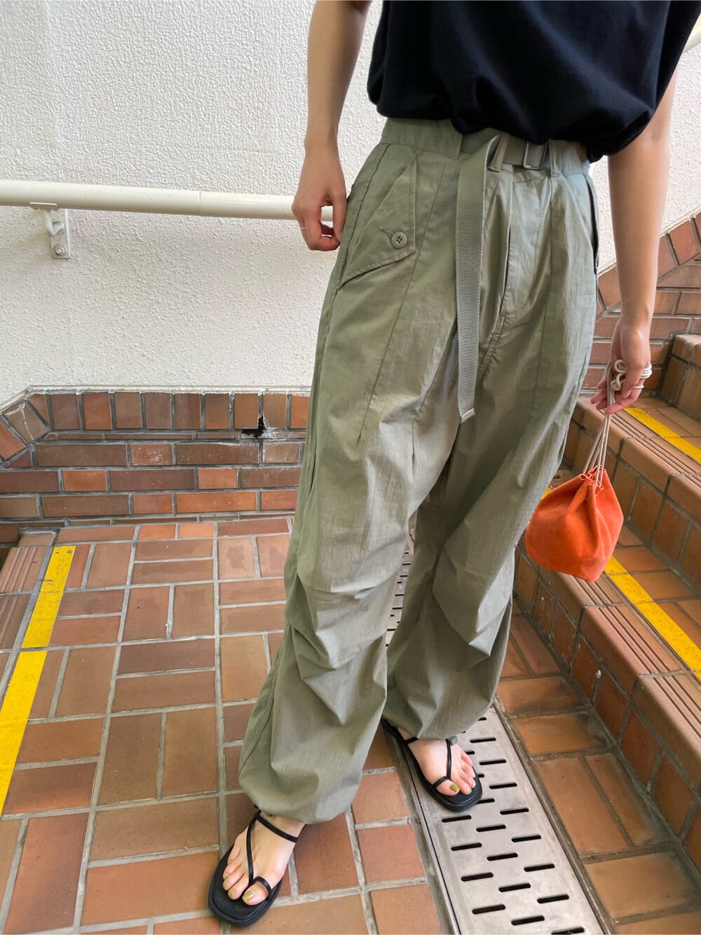 ブラック系のサンダル、オレンジ系のハンドバッグ、ベージュ系のその他パンツを着用したレディースの春コーディネートの10枚目の写真