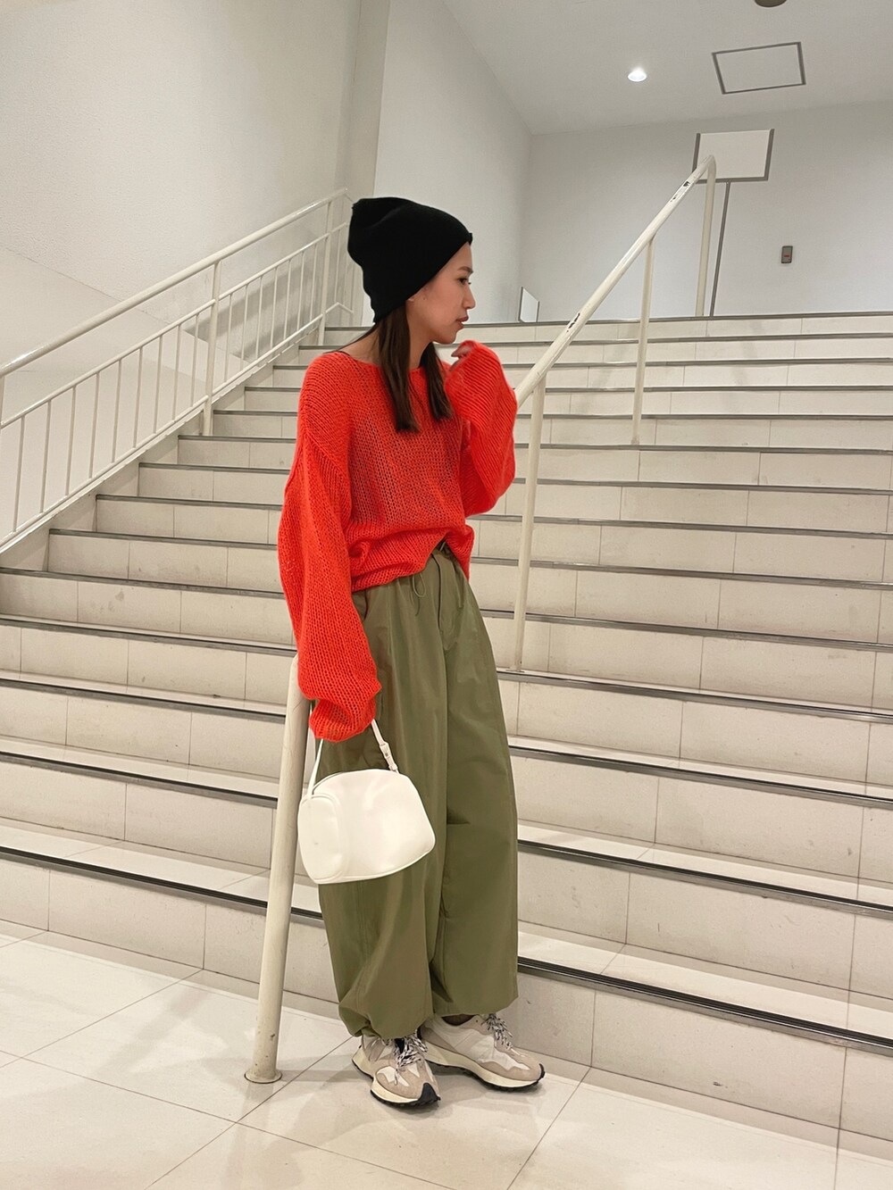グリーン系のカーゴパンツ、ホワイト系のハンドバッグ、オレンジ系のニット/セーターを着用したレディースの冬コーディネートの3枚目の写真
