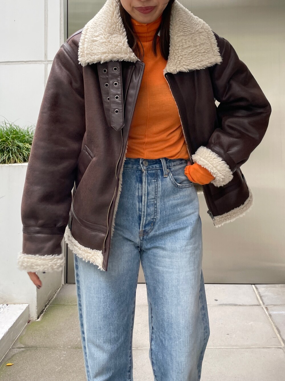 ブラウン系のムートンコート、ブルー系のデニムパンツ、ブラック系のブーツを着用したレディースの秋コーディネートの7枚目の写真