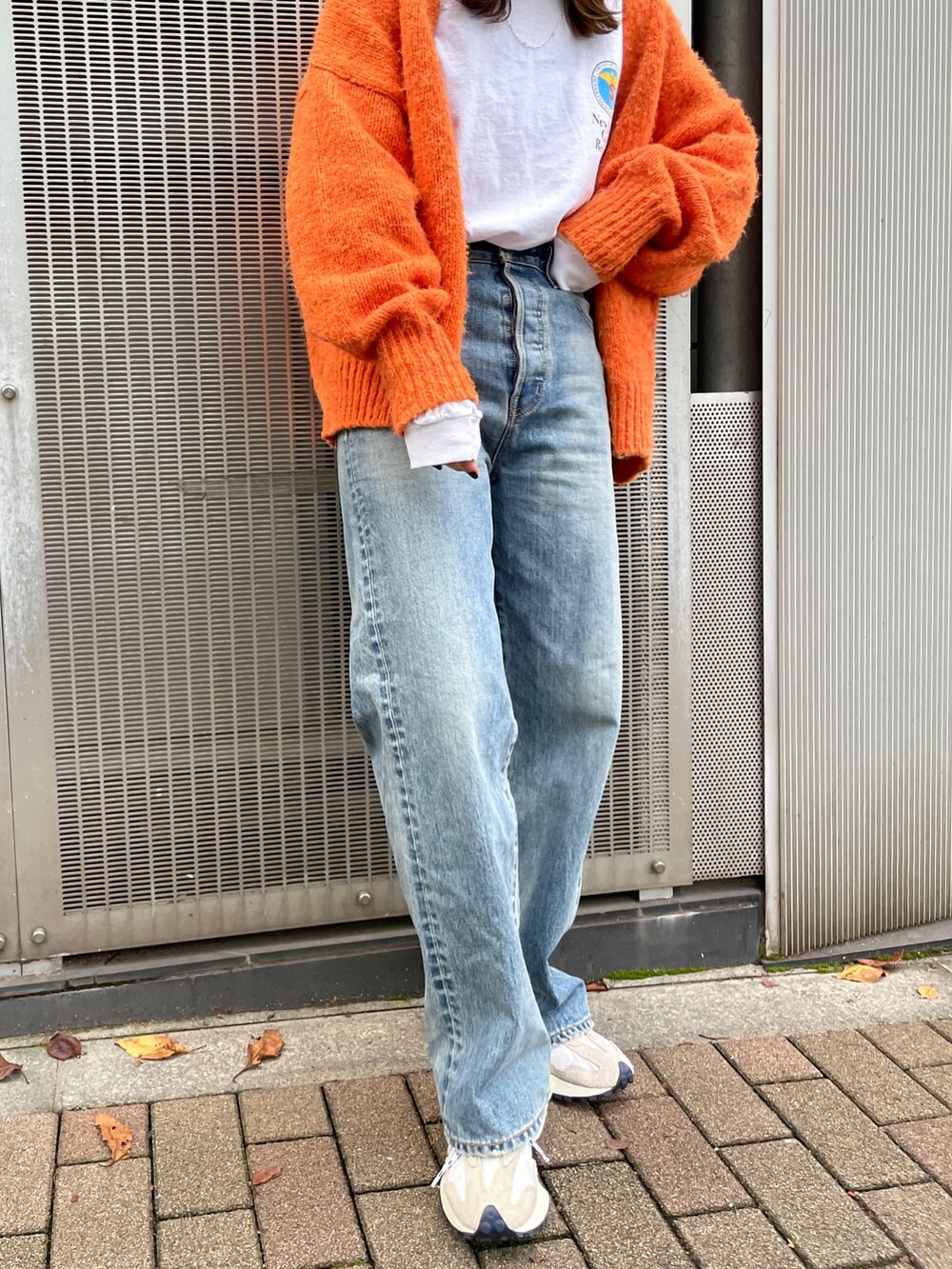 オレンジ系のカーディガン/ボレロ、ブルー系のデニムパンツ、ホワイト系のTシャツ/カットソーを着用したレディースの秋コーディネートの8枚目の写真