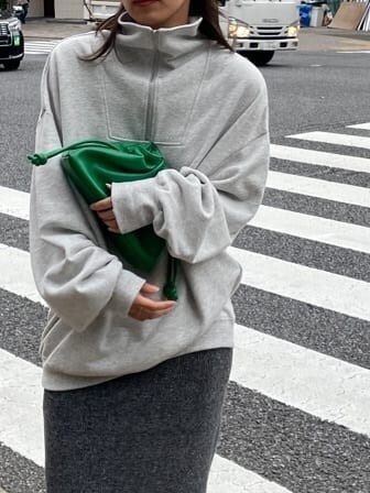 グリーン系のクラッチバッグ、グレー系のスウェット、グレー系のスカートを着用したレディースの秋コーディネートの6枚目の写真