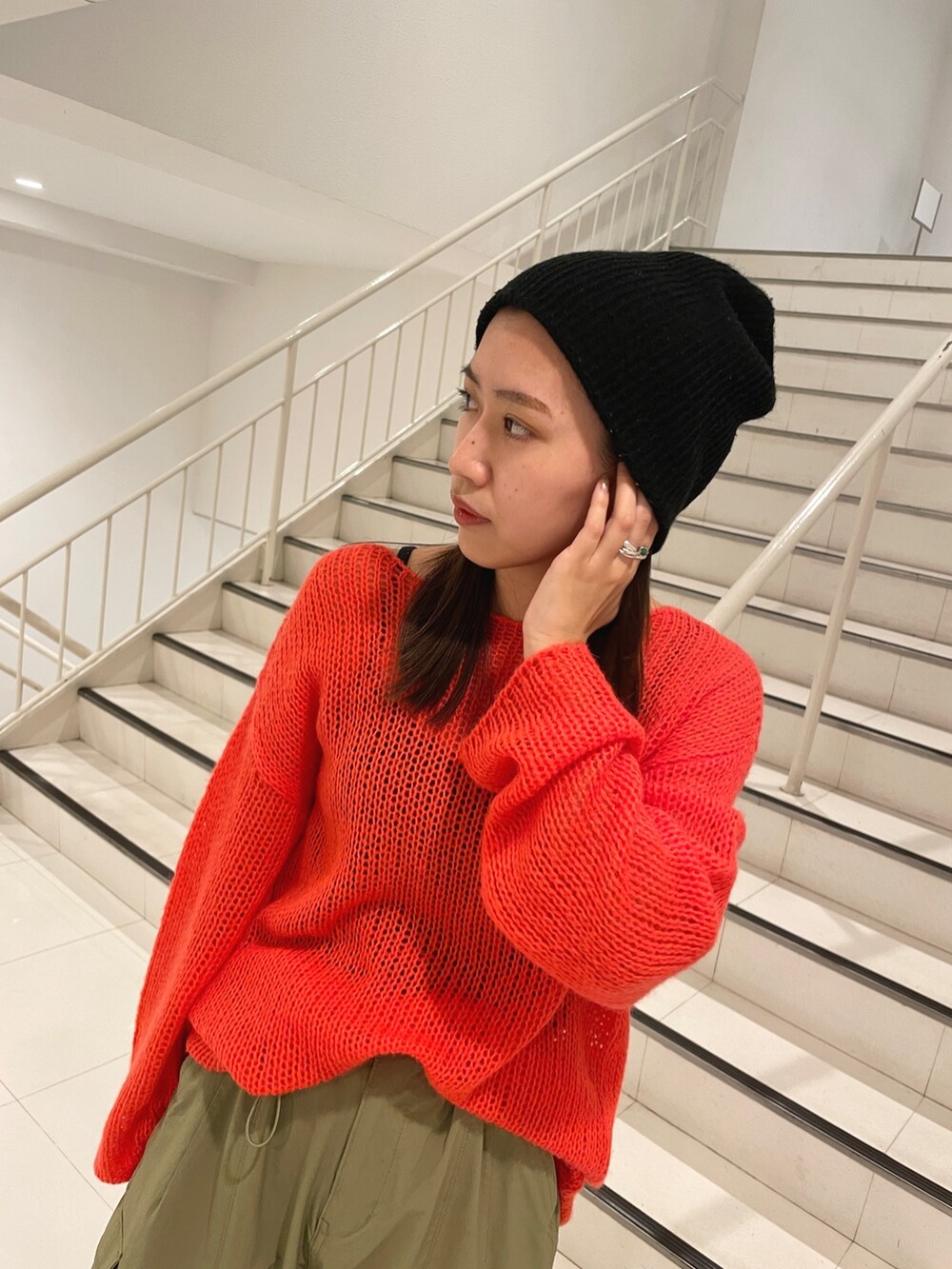 グリーン系のカーゴパンツ、ホワイト系のハンドバッグ、オレンジ系のニット/セーターを着用したレディースの冬コーディネートの5枚目の写真