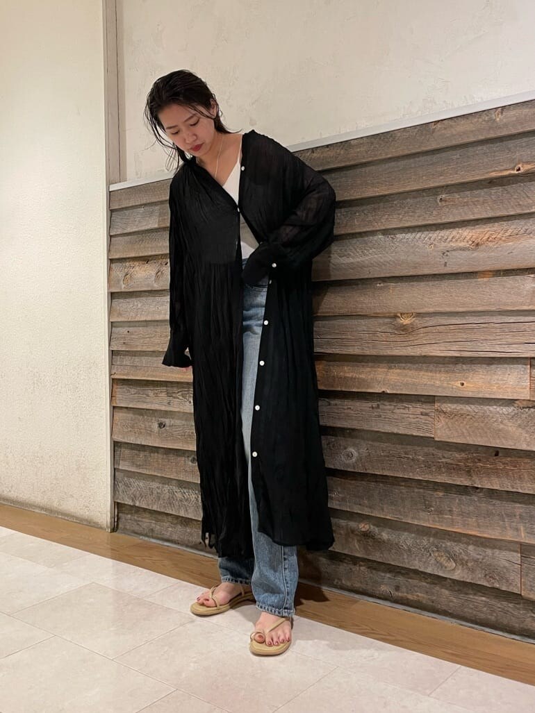 ブルー系のデニムパンツ、ブラック系のワンピース、グリーン系のサンダルを着用したレディースの夏コーディネートの3枚目の写真