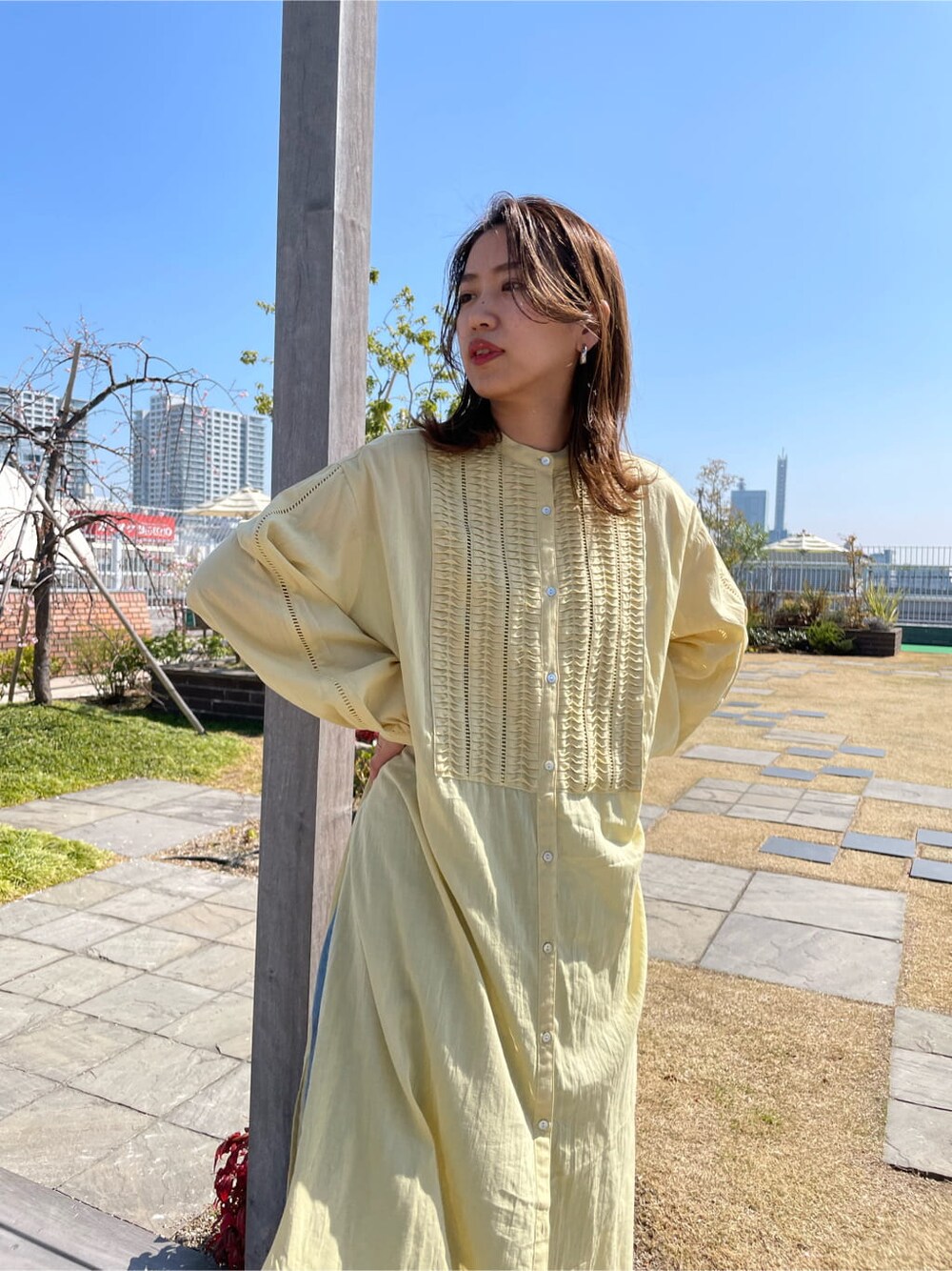 イエロー系のワンピース、ブラック系のサンダル、ブルー系のデニムパンツを着用したレディースの春コーディネートの5枚目の写真