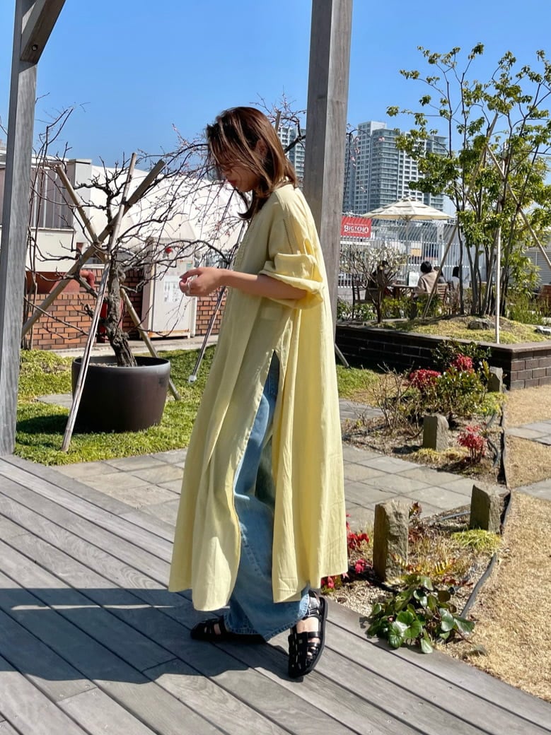 イエロー系のワンピース、ブラック系のサンダル、ブルー系のデニムパンツを着用したレディースの春コーディネートの4枚目の写真