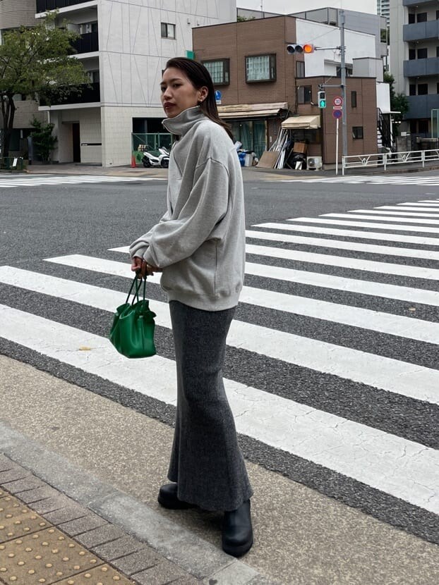グリーン系のクラッチバッグ、グレー系のスウェット、グレー系のスカートを着用したレディースの秋コーディネートの3枚目の写真