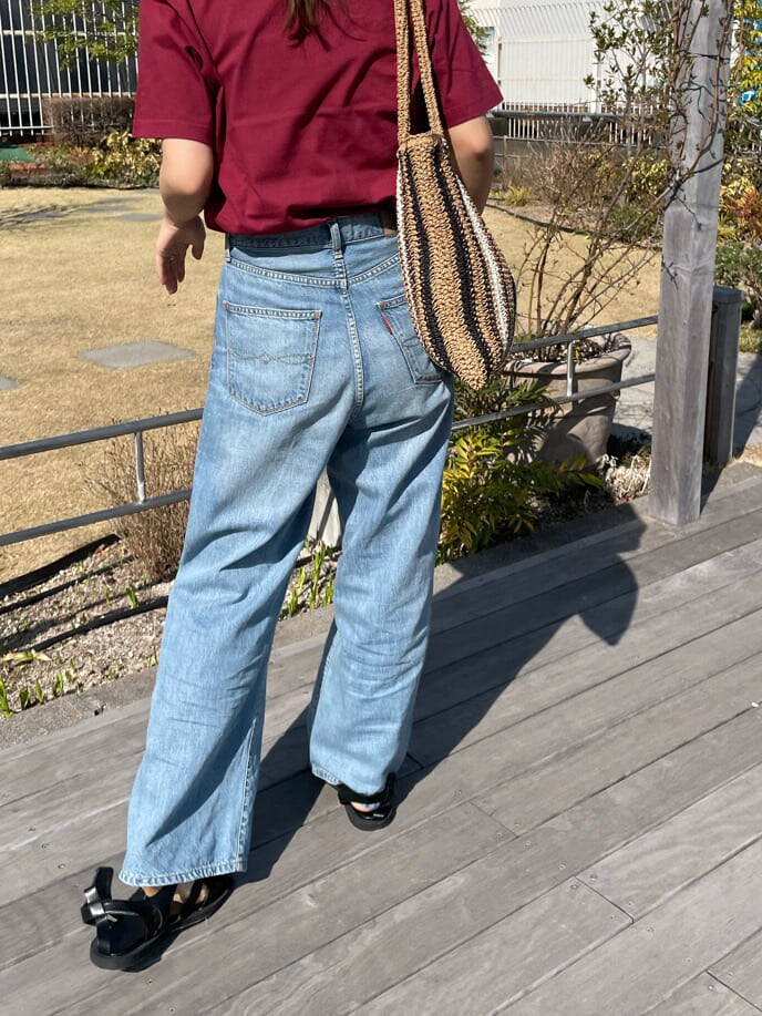 ベージュ系のトートバッグ、ブラック系のサンダル、ブルー系のデニムパンツを着用したレディースの春コーディネートの5枚目の写真