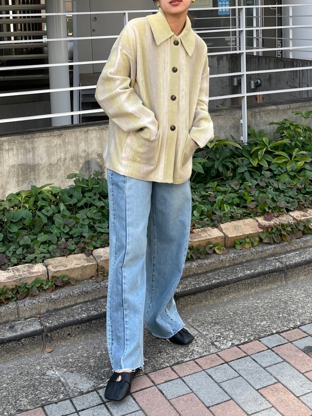 ブルー系のデニムパンツ、グリーン系のカーディガン/ボレロ、ブラック系のパンプスを着用したレディースの秋コーディネートの2枚目の写真