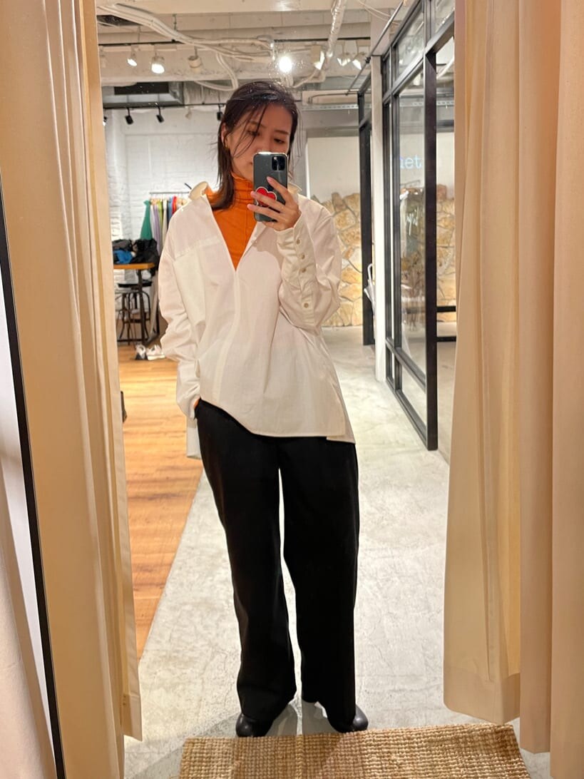 グレー系のスラックス、ホワイト系のシャツ/ブラウス、オレンジ系のTシャツ/カットソーを着用したレディースの秋コーディネートの2枚目の写真